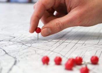 Placing red push pins into city street map.