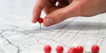 Placing red push pins into city street map.