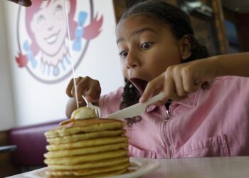 A kid enjoying a big stack of pan cakes at Wendys