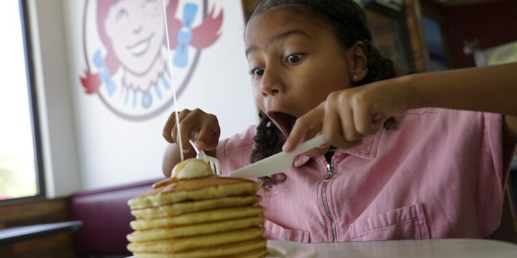 A kid enjoying a big stack of pan cakes at Wendys