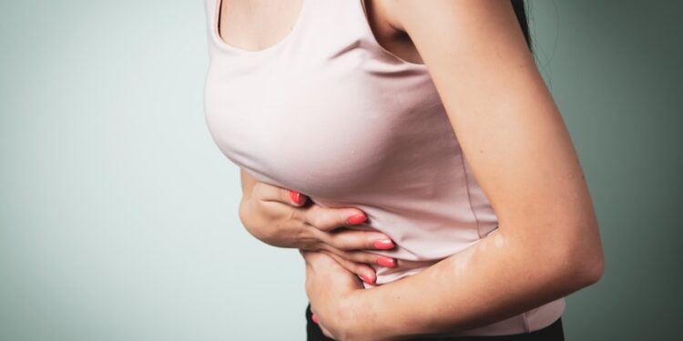 woman with a pain in a hand on a gray background. health and medicine.