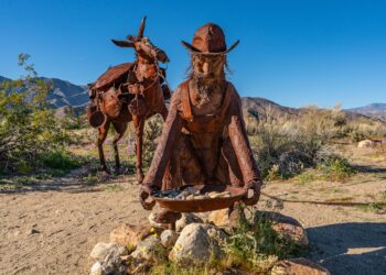 A miner and his burro stride across the sand, echoing the hardship and hope of California’s frontier days.