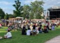 A concert crowd seating on the grass at an open air classical music concert