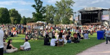 A concert crowd seating on the grass at an open air classical music concert