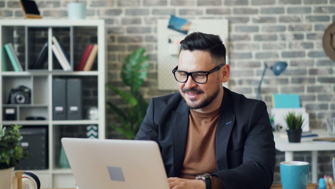 Bearded young man working with laptop then stretching arms relaxing in office