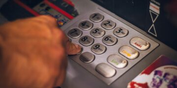 Iemand belt met een telefoon terwijl een bankpas op tafel ligt