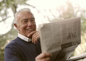 Oudere man bekijkt een brief met financiele gegevens aan de keukentafel