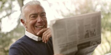 Oudere man bekijkt een brief met financiele gegevens aan de keukentafel