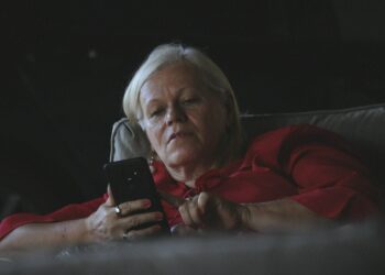 Oudere vrouw kijkt kritisch naar een bericht op haar smartphone