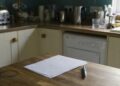 Brief van de gemeente op een keukentafel naast een pen en een leesbril