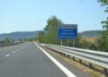 Grijze flitspaal langs een provinciale weg bij een kruispunt