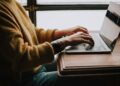 Iemand bekijkt een e-mail met een enquête op een laptop aan de keukentafel