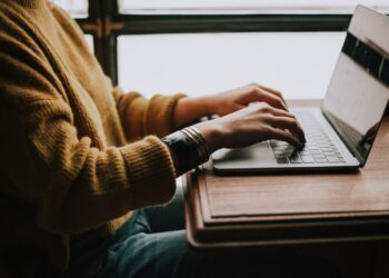 Iemand bekijkt een e-mail met een enquête op een laptop aan de keukentafel