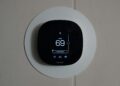 Thermostaat aan de muur van een woonkamer met de verwarming aan