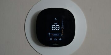 Thermostaat aan de muur van een woonkamer met de verwarming aan