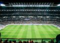 Trainer langs de zijlijn tijdens een voetbalwedstrijd in een vol stadion