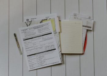 Iemand vult aan een tafel een klachtformulier in met financiële papieren ernaast