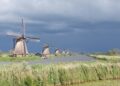 Donkere onweerswolken boven een Nederlandse polder met een weg
