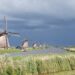 Donkere onweerswolken boven een Nederlandse polder met een weg
