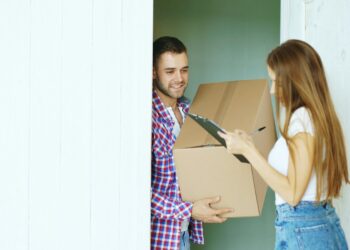 Pakketbezorger met een doos voor de deur van een woning