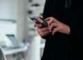 Hand met een smartphone waarop een binnengekomen bericht staat
