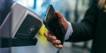 Telefoon die contactloos betaalt bij een betaalautomaat in een winkel