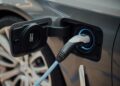 Elektrische auto aan een laadpaal bij een woning in de avond