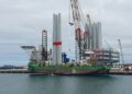 Windmolenpark op de Noordzee met een vrachtschip aan de horizon