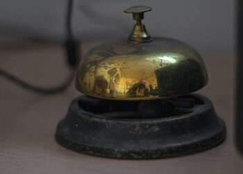 Hotelreceptie met een bel op de balie en sleutels aan de wand
