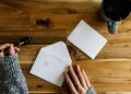 Iemand aan de keukentafel leest een officiële brief met loonstroken ernaast