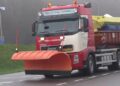 Strooiwagen met oranje sneeuwschuiver op een winterse weg