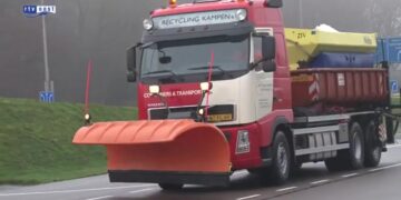 Strooiwagen met oranje sneeuwschuiver op een winterse weg