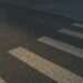Voetganger steekt in het donker over op een zebrapad terwijl een auto nadert